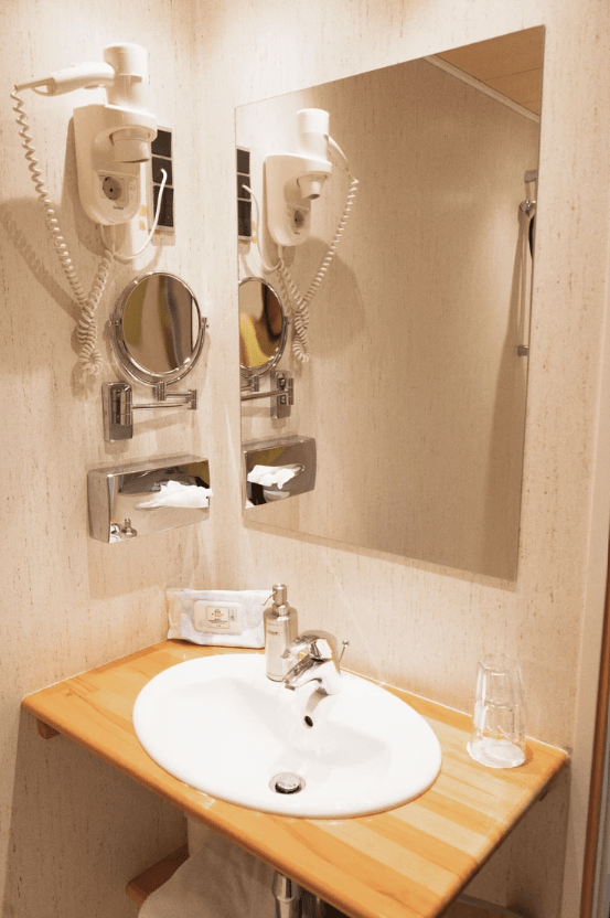 billede af toilet på værelse. dejligt lyst. træ borplade. stort spejl. hårtørrer. vandglas ved siden af vask